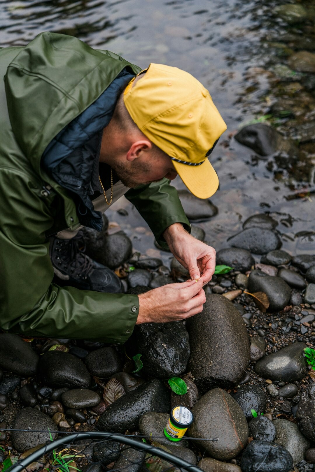 Researcher crouching by a stream collecting a water sample in a test tube