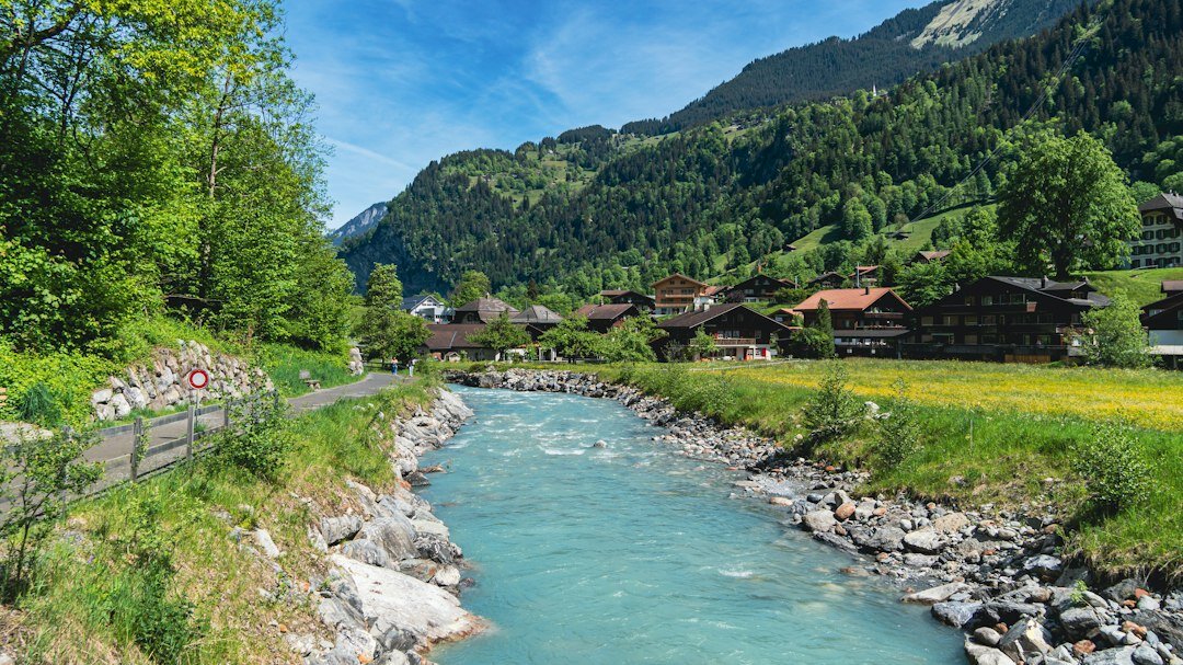 Alpine river running through a Swiss valley with industrial pipes visible on the bank